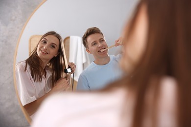 Photo of Young couple getting ready together near mirror at home