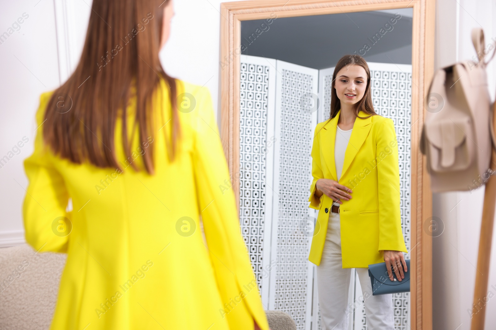 Getting ready. Young woman trying on clothes near mirror at home Photo of Getting ready. Young woman trying on clothes near mirror at home