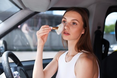 Photo of Getting ready. Young woman applying makeup in car
