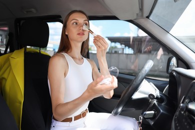 Photo of Getting ready. Young woman applying makeup in car