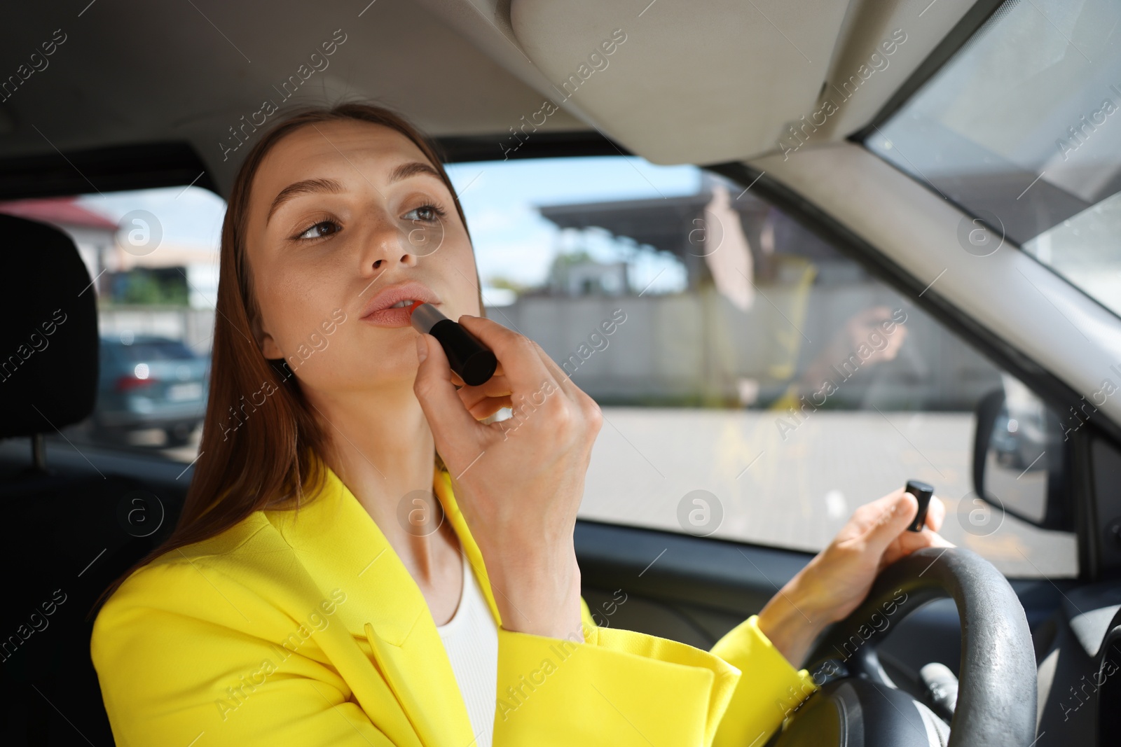 Getting ready. Young woman applying lipstick in car Photo of Getting ready. Young woman applying lipstick in car