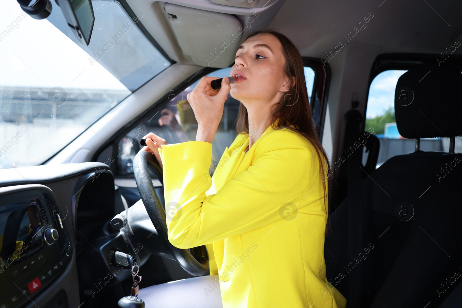 Getting ready. Young woman applying lipstick in car Photo of Getting ready. Young woman applying lipstick in car