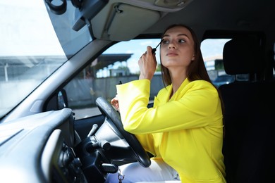 Photo of Getting ready. Young woman applying mascara in car