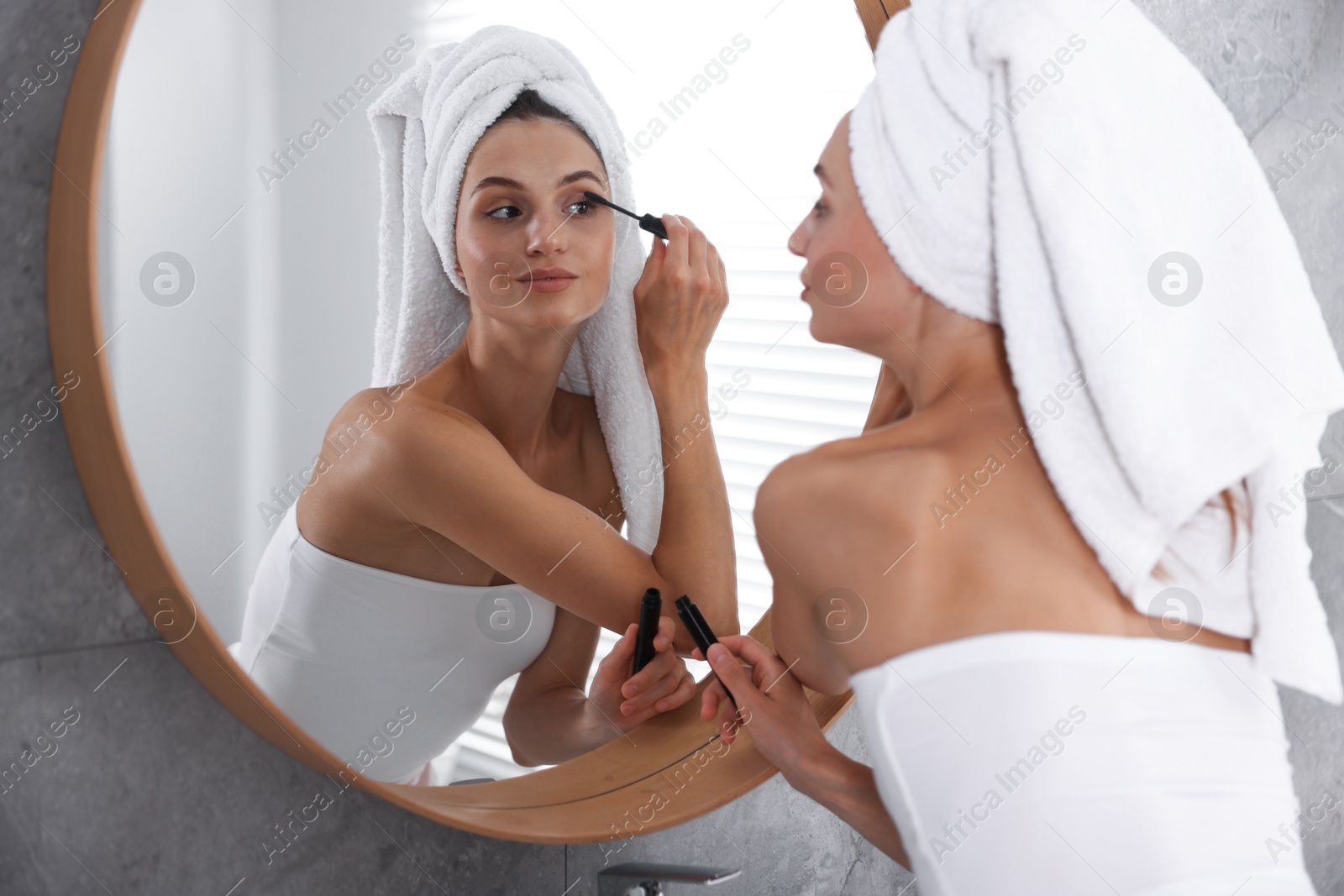 Getting ready. Young woman applying mascara near mirror at home Photo of Getting ready. Young woman applying mascara near mirror at home