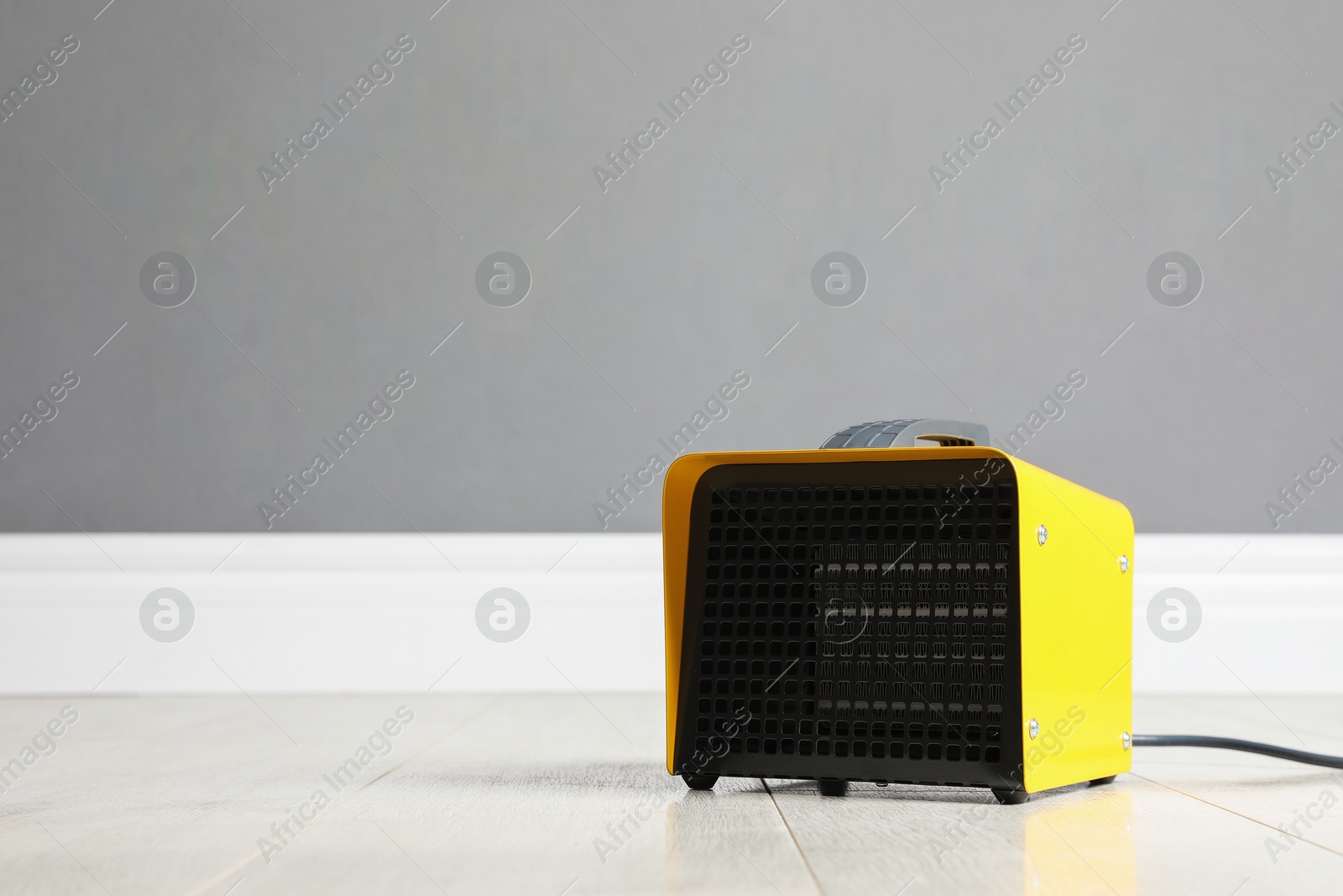 New modern electric heater on floor in room, space for text Photo of New modern electric heater on floor in room, space for text