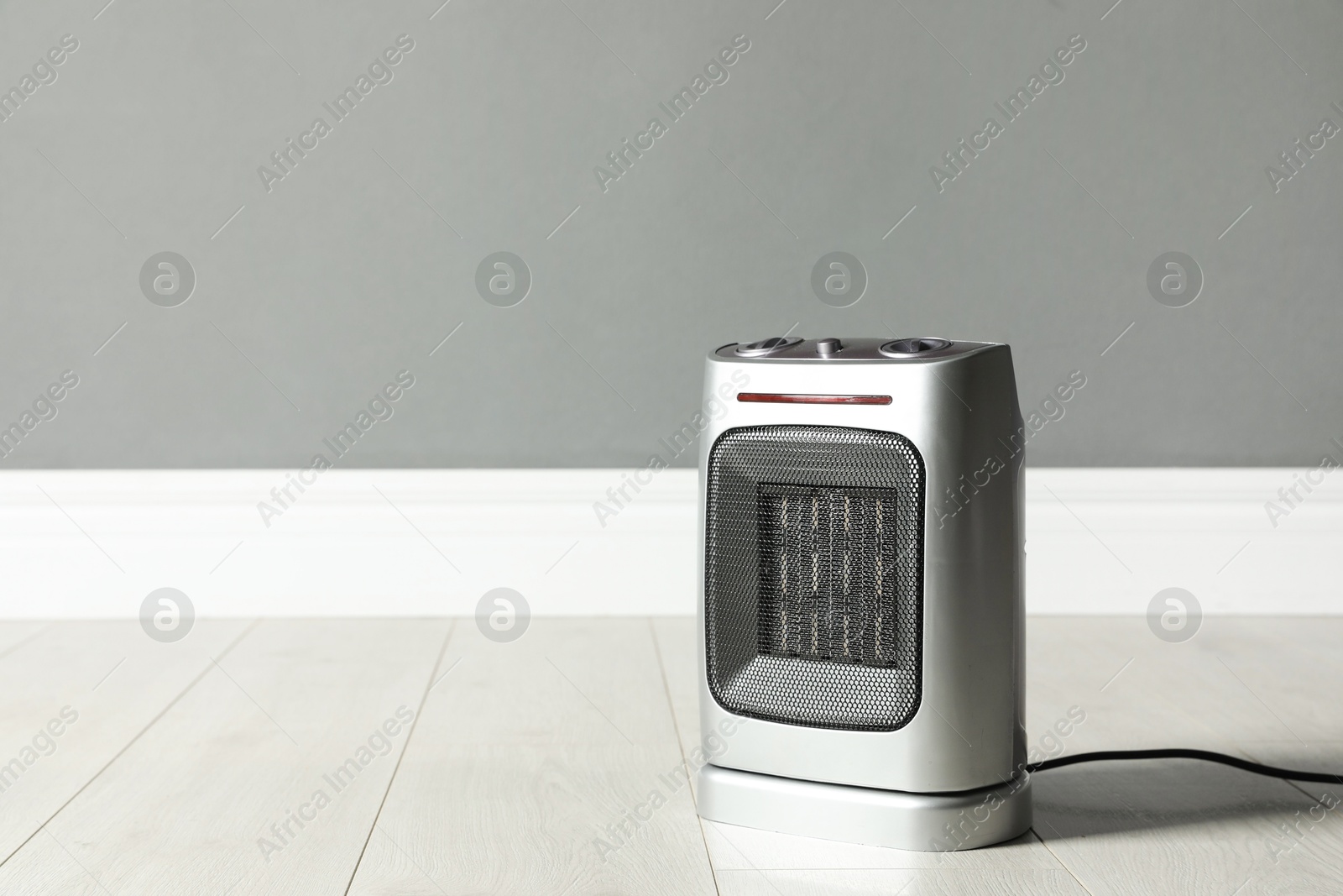 Photo of Modern electric fan heater on floor in room, space for text