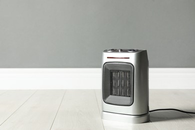 Photo of Modern electric fan heater on floor in room, space for text