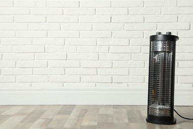 Photo of New modern electric heater on floor in room, space for text