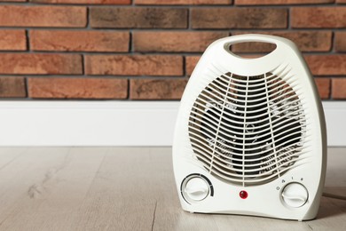 Photo of Modern electric fan heater on floor in room, space for text