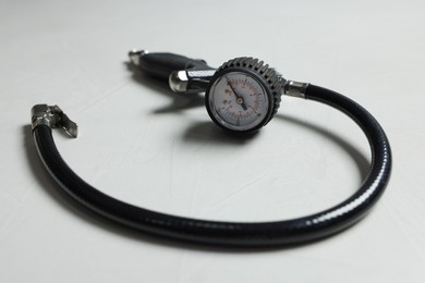 Photo of One tire inflation gun with gauge on light background, closeup