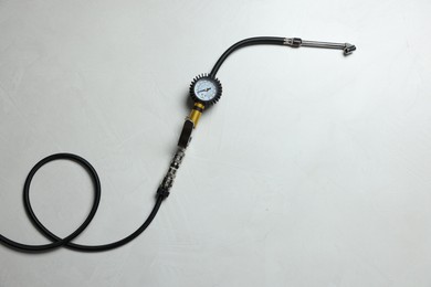 Photo of One tire inflation gun with gauge on light background, top view. Space for text