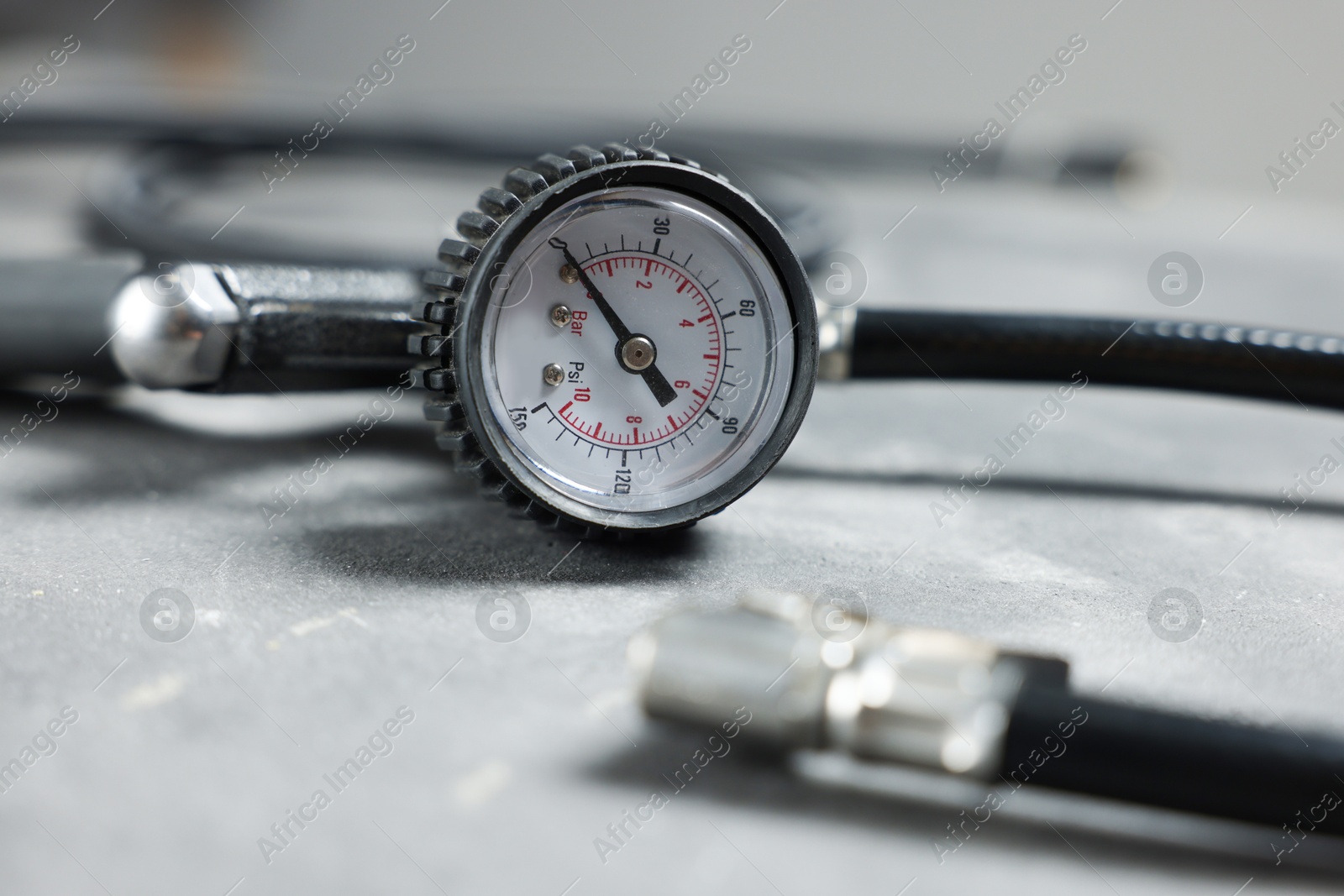 One tire inflation gun with gauge on grey background, closeup Photo of One tire inflation gun with gauge on grey background, closeup