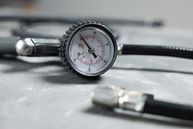 Photo of One tire inflation gun with gauge on grey background, closeup