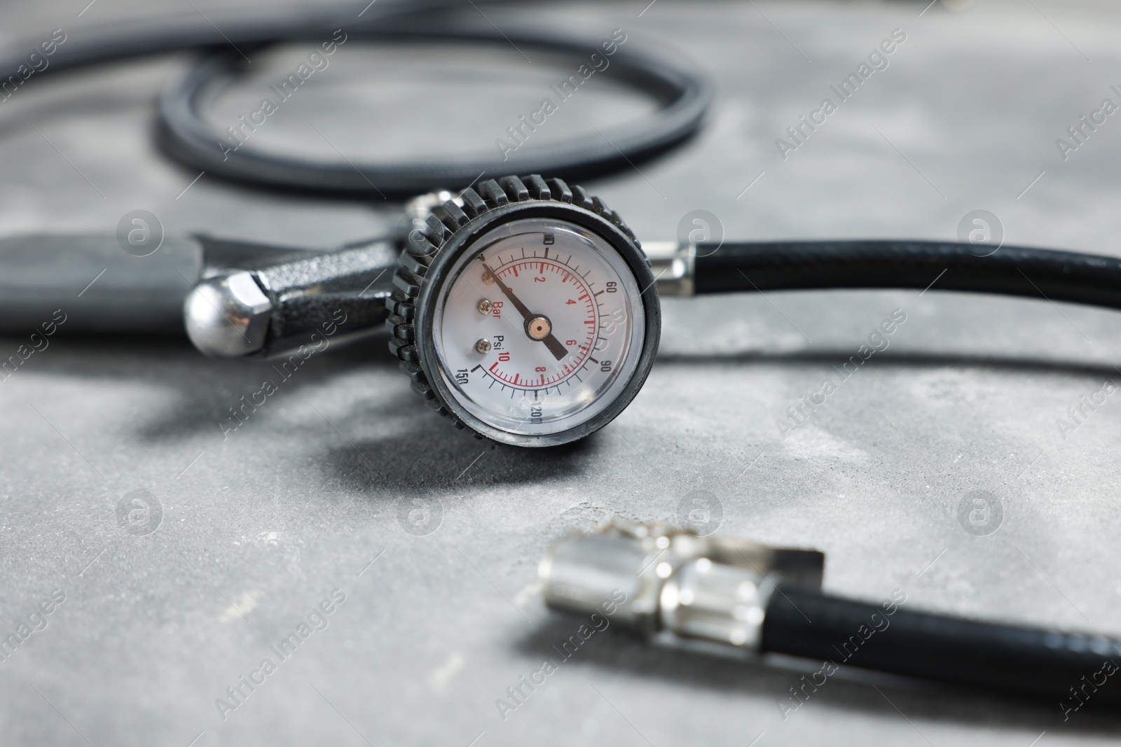 One tire inflation gun with gauge on grey background, closeup Photo of One tire inflation gun with gauge on grey background, closeup
