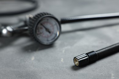 Photo of One tire inflation gun with gauge on grey background, closeup