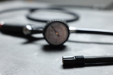 Photo of One tire inflation gun with gauge on grey background, closeup