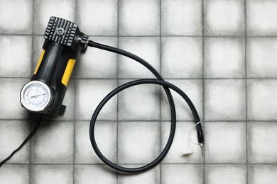 Photo of One tire inflation gun with gauge on light tiled background, top view. Space for text
