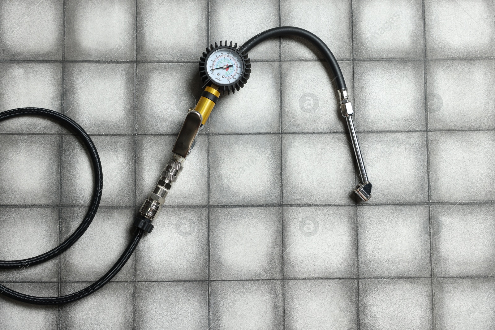 One tire inflation gun with gauge on light tiled background, top view Photo of One tire inflation gun with gauge on light tiled background, top view