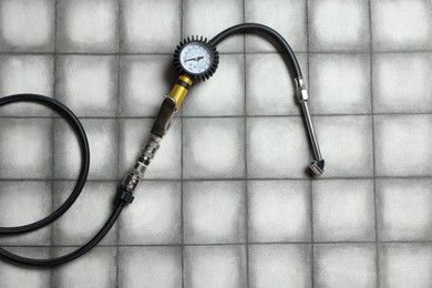 Photo of One tire inflation gun with gauge on light tiled background, top view