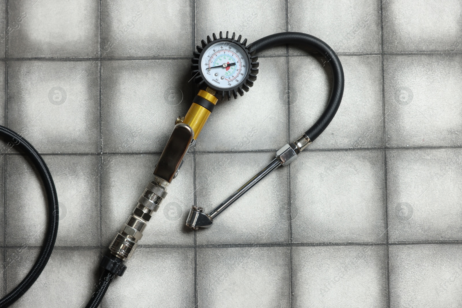 One tire inflation gun with gauge on light tiled background, top view Photo of One tire inflation gun with gauge on light tiled background, top view