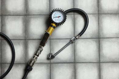 Photo of One tire inflation gun with gauge on light tiled background, top view