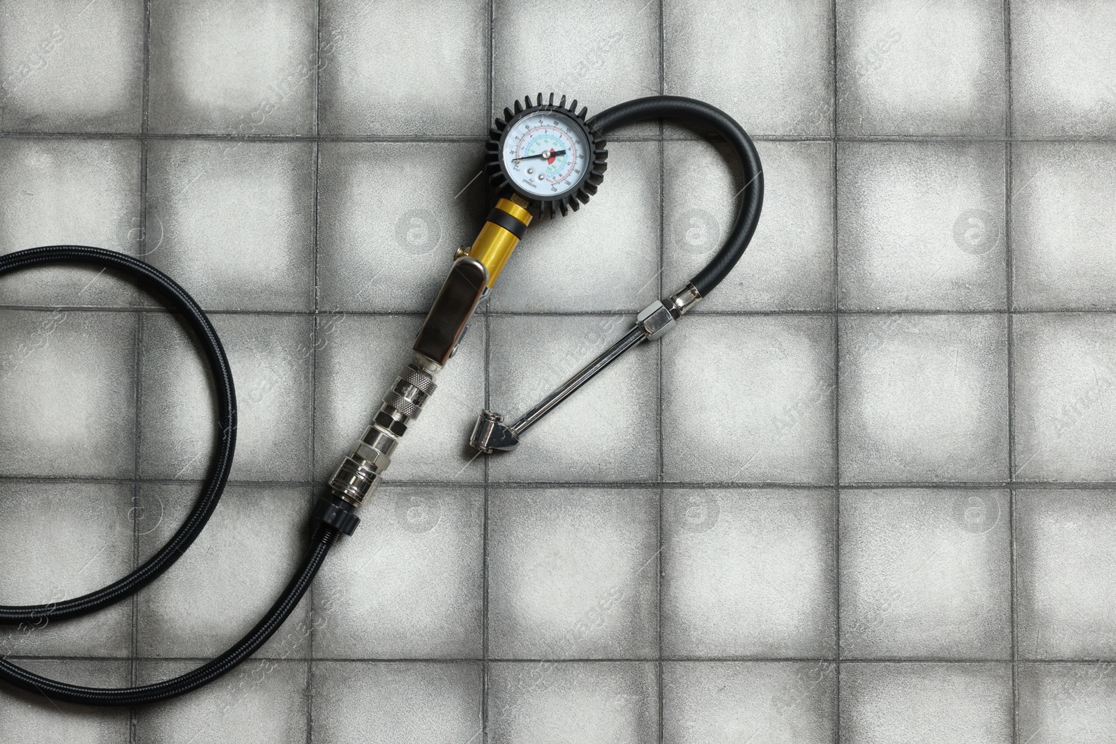 One tire inflation gun with gauge on light tiled background, top view. Space for text Photo of One tire inflation gun with gauge on light tiled background, top view. Space for text