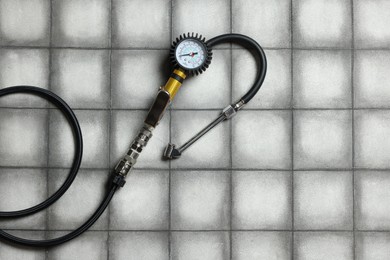 Photo of One tire inflation gun with gauge on light tiled background, top view. Space for text