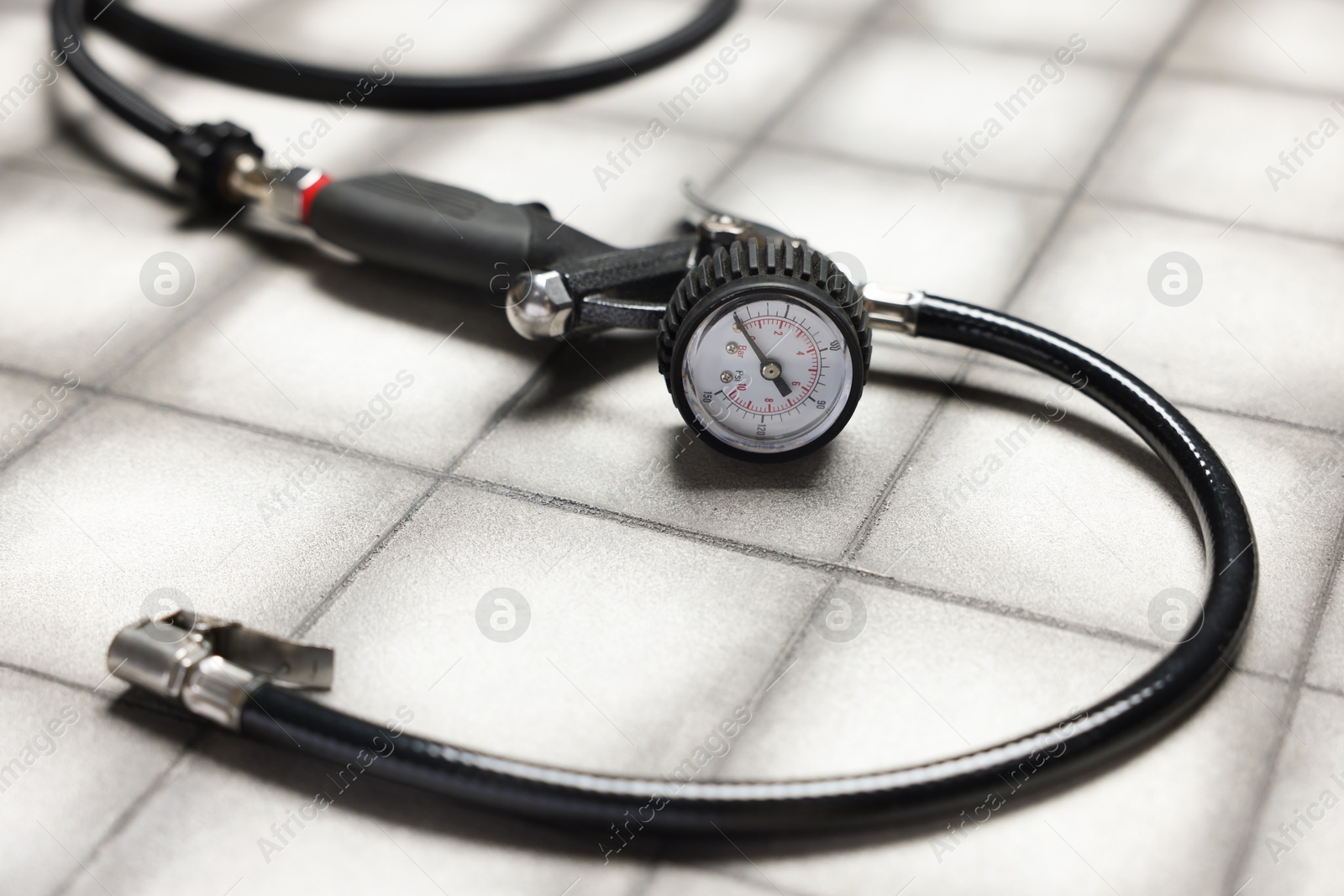One tire inflation gun with gauge on light tiled background, closeup Photo of One tire inflation gun with gauge on light tiled background, closeup