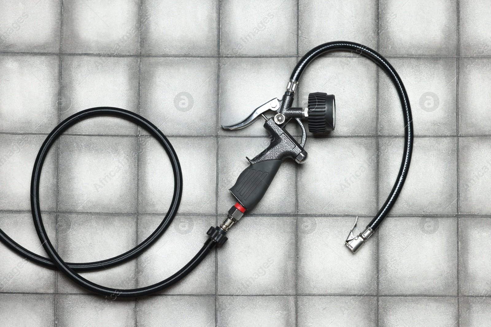 One tire inflation gun with gauge on light tiled background, top view Photo of One tire inflation gun with gauge on light tiled background, top view