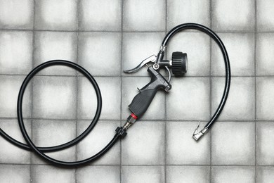 Photo of One tire inflation gun with gauge on light tiled background, top view