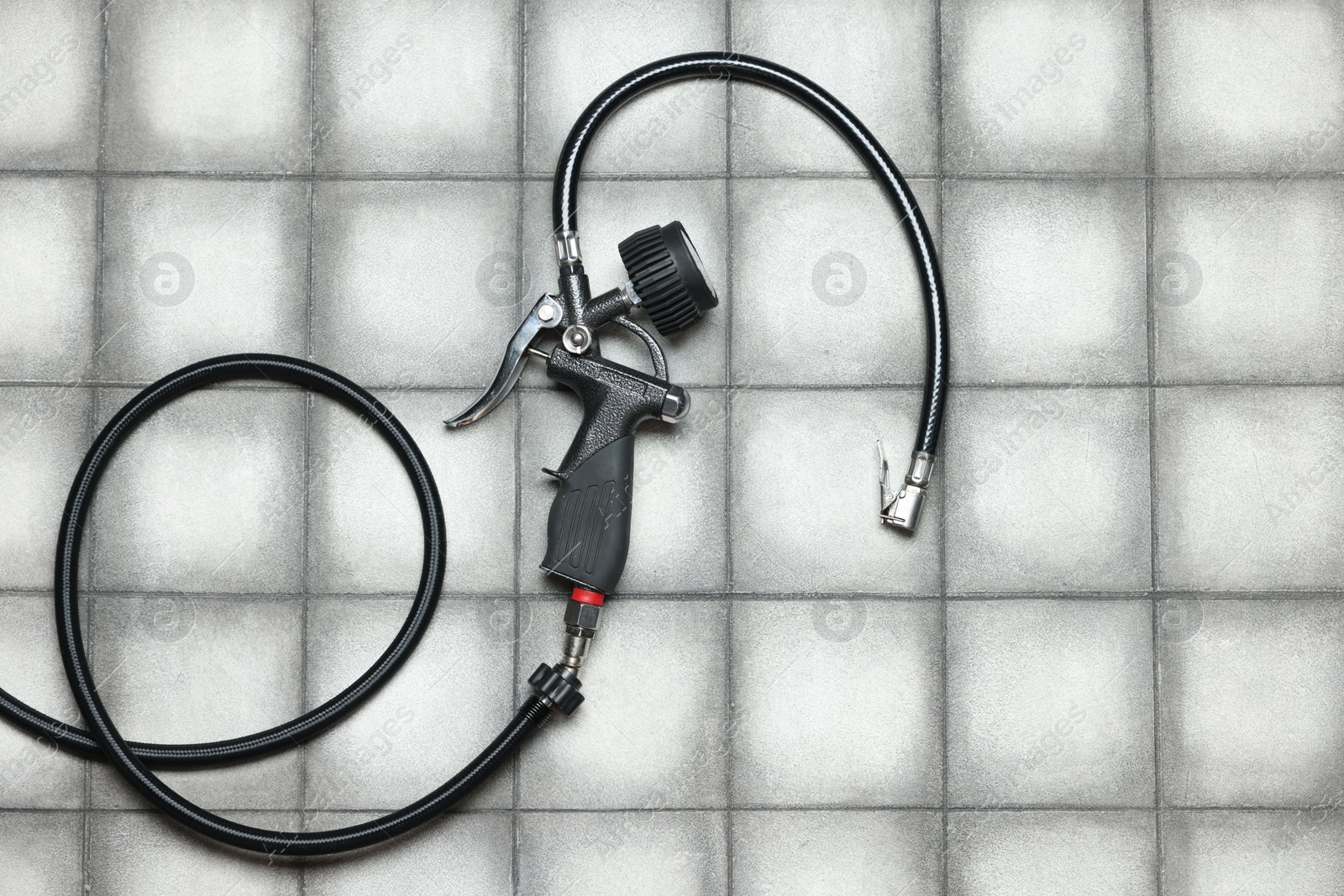One tire inflation gun with gauge on light tiled background, top view Photo of One tire inflation gun with gauge on light tiled background, top view