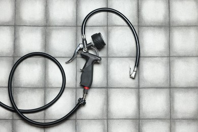 Photo of One tire inflation gun with gauge on light tiled background, top view