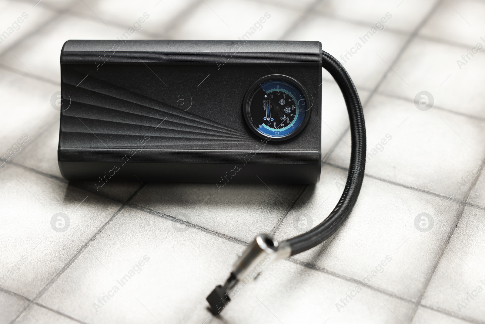 One modern tire inflator on light tiled background, closeup Photo of One modern tire inflator on light tiled background, closeup