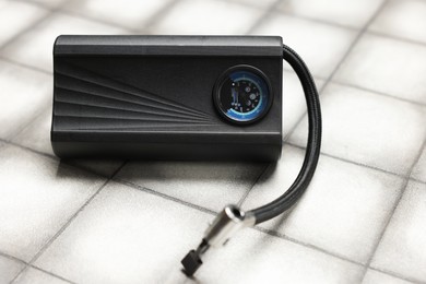 Photo of One modern tire inflator on light tiled background, closeup