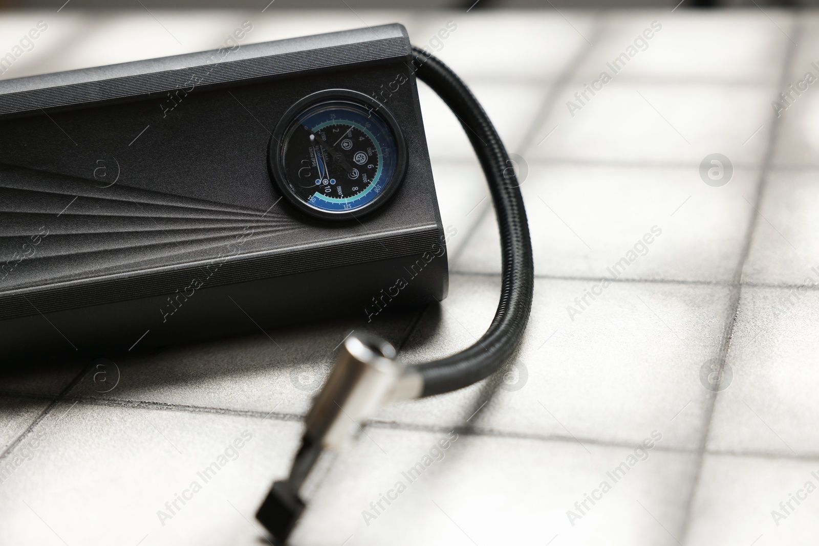 One tire inflator on light tiled background, closeup Photo of One tire inflator on light tiled background, closeup