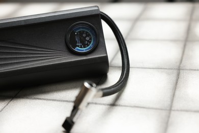 Photo of One tire inflator on light tiled background, closeup