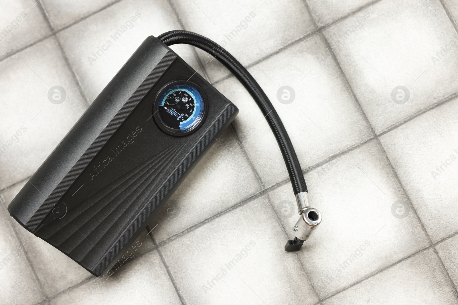 One tire inflator on light tiled background, closeup. Space for text Photo of One tire inflator on light tiled background, closeup. Space for text