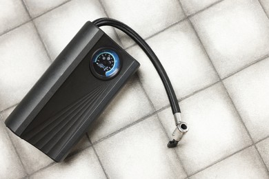Photo of One tire inflator on light tiled background, closeup. Space for text