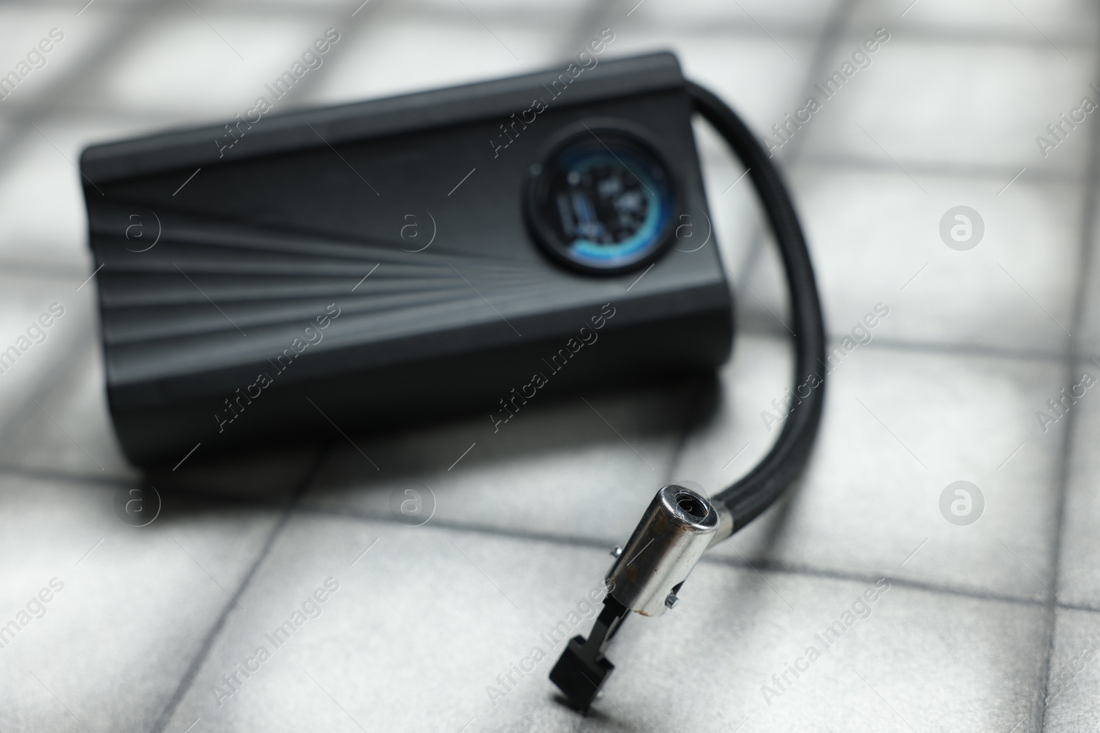 Photo of One modern tire inflator on light tiled background, closeup