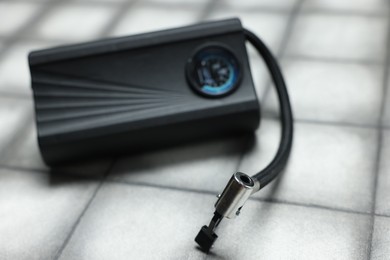 Photo of One modern tire inflator on light tiled background, closeup
