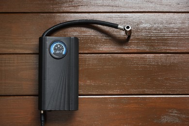Photo of One tire inflator on wooden background, top view. Space for text