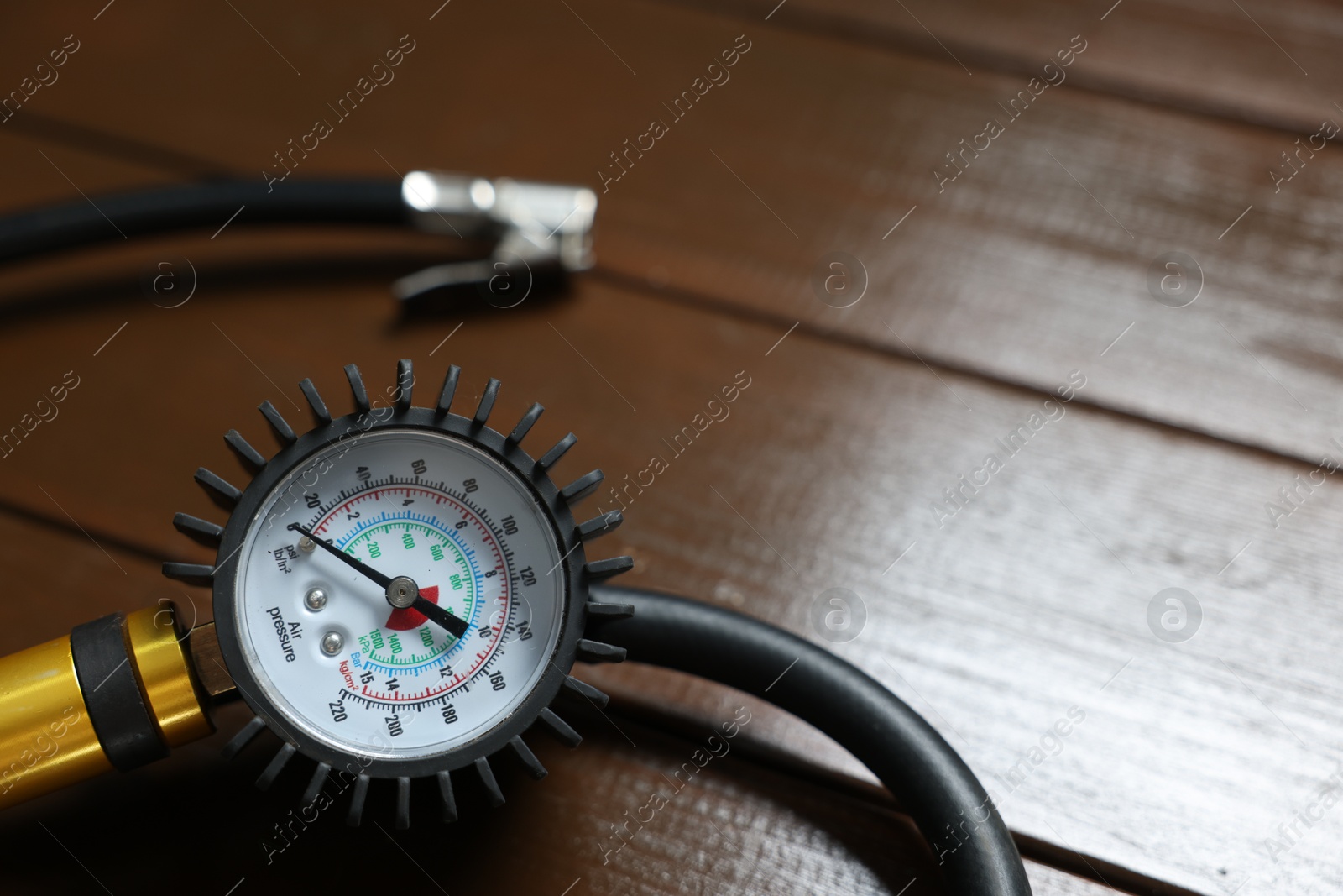 One tire inflation gun with gauge on wooden background, closeup. Space for text Photo of One tire inflation gun with gauge on wooden background, closeup. Space for text