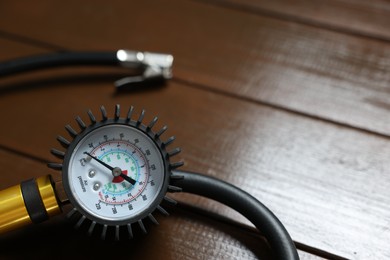 Photo of One tire inflation gun with gauge on wooden background, closeup. Space for text
