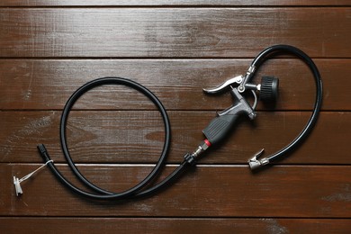 Photo of One tire inflation gun with gauge on wooden background, top view