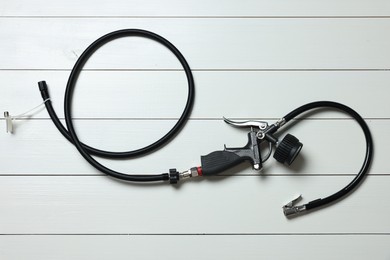 Photo of One tire inflation gun with gauge on white wooden background, top view