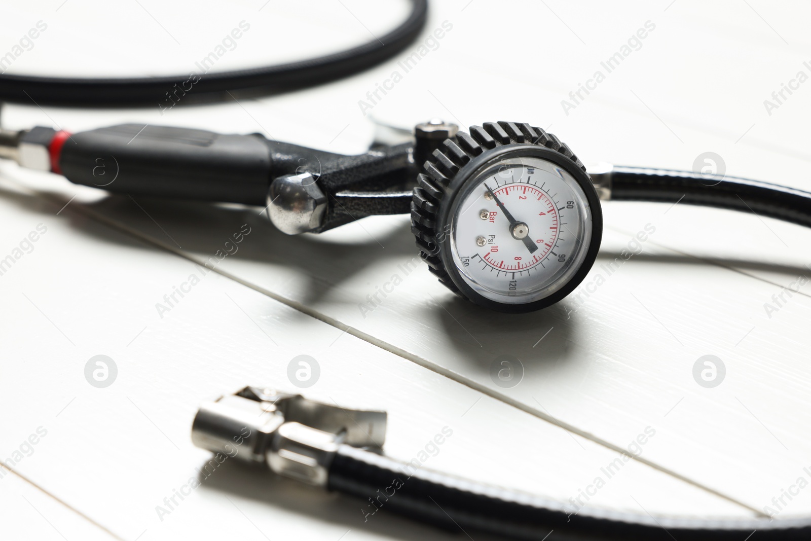 One tire inflation gun with gauge on white wooden background, closeup Photo of One tire inflation gun with gauge on white wooden background, closeup