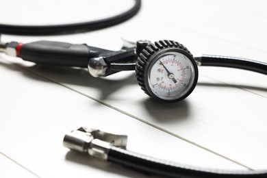 Photo of One tire inflation gun with gauge on white wooden background, closeup