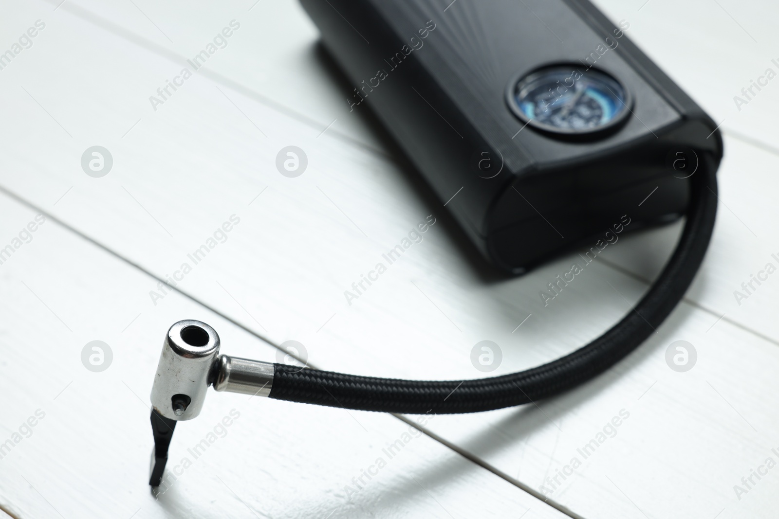 Photo of One modern tire inflator on white wooden background, closeup