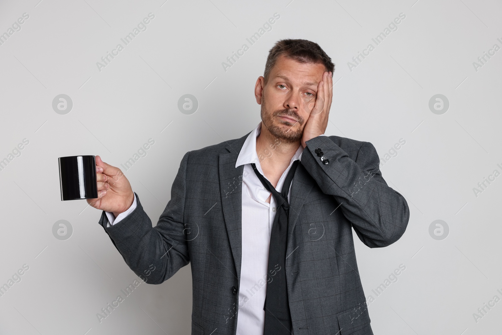 Photo of Man with cup of drink suffering from hangover on white background
