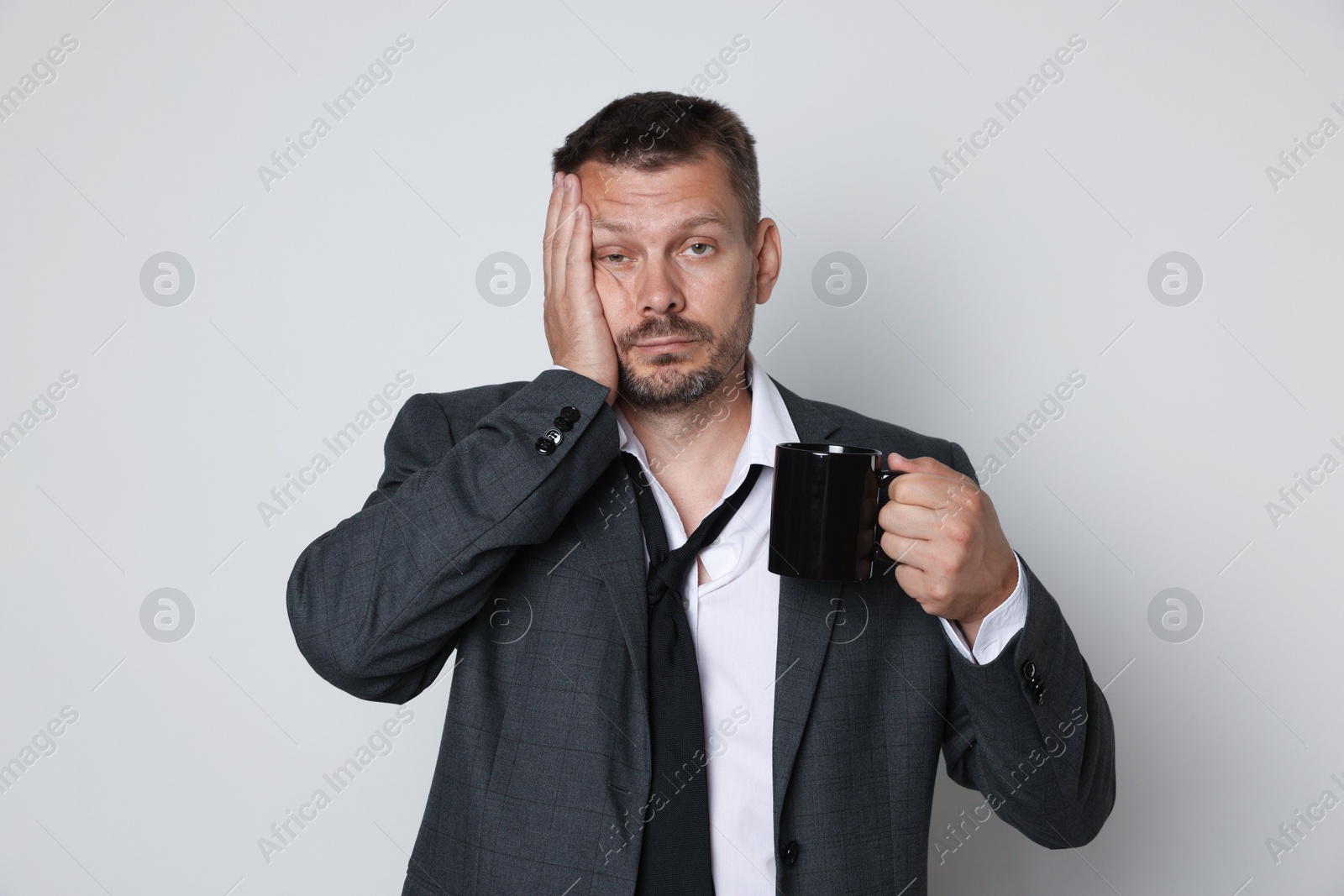 Photo of Man with cup of drink suffering from hangover on white background